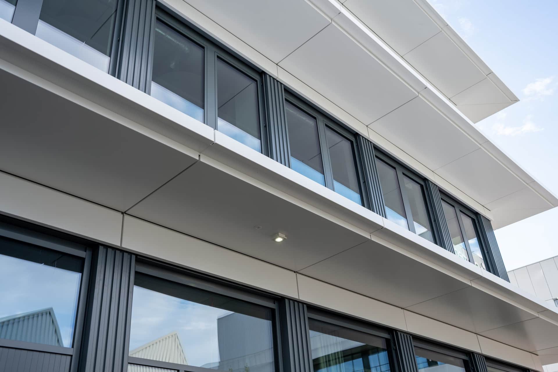 Auskragende weisse Fassadenbänder einer Metallfassade in der Perspektive