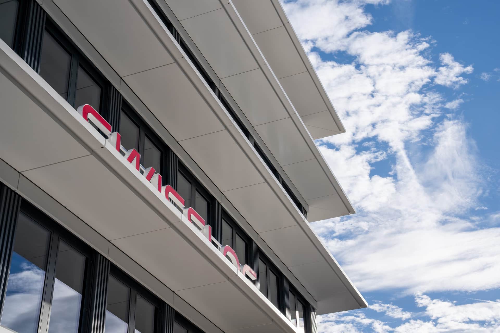 Auskragende Bänder einer Metallfassade vor bewölktem Himmel