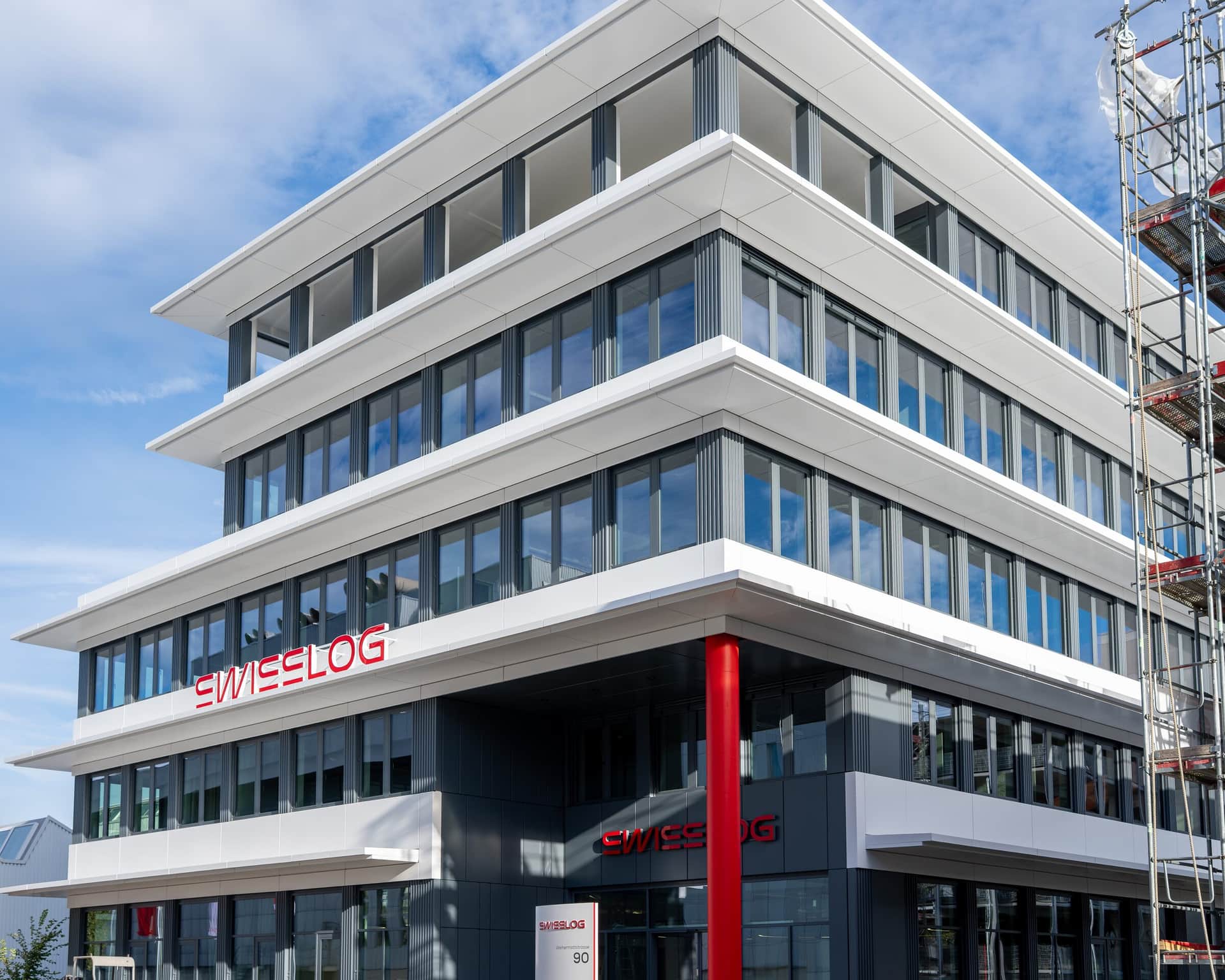 Bürogebäude mit Metallfassade aus weissen Fassadenbändern und roter Stütze