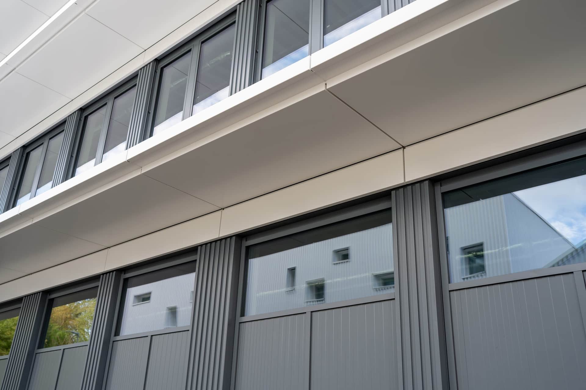 Detail einer Metallfassade mit auskragendem Band und Fensterband