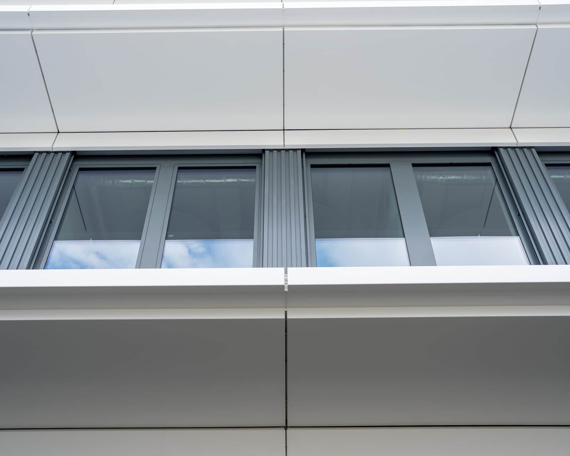 Fassadendetail mit Fenstern zwischen weissen Blechverkleidungen