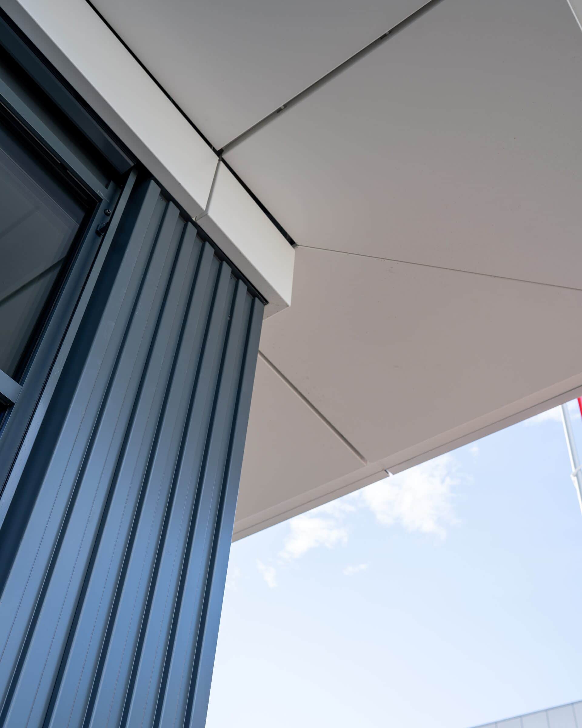 Eckdetail einer Metallfassade mit Profilblech und weisser Untersicht