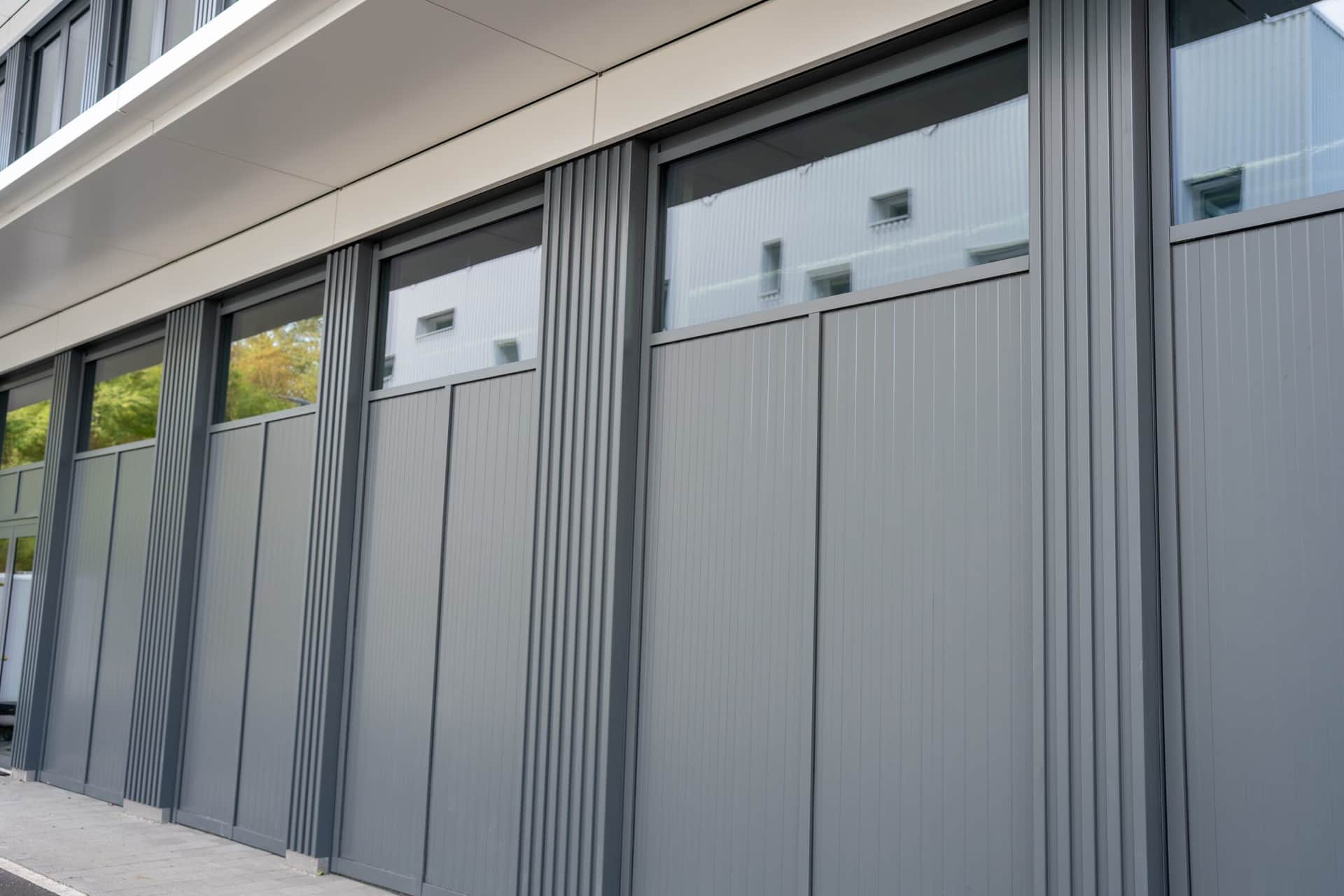 Erdgeschoss mit Metallfassade aus grauen Kassetten und Profilblech