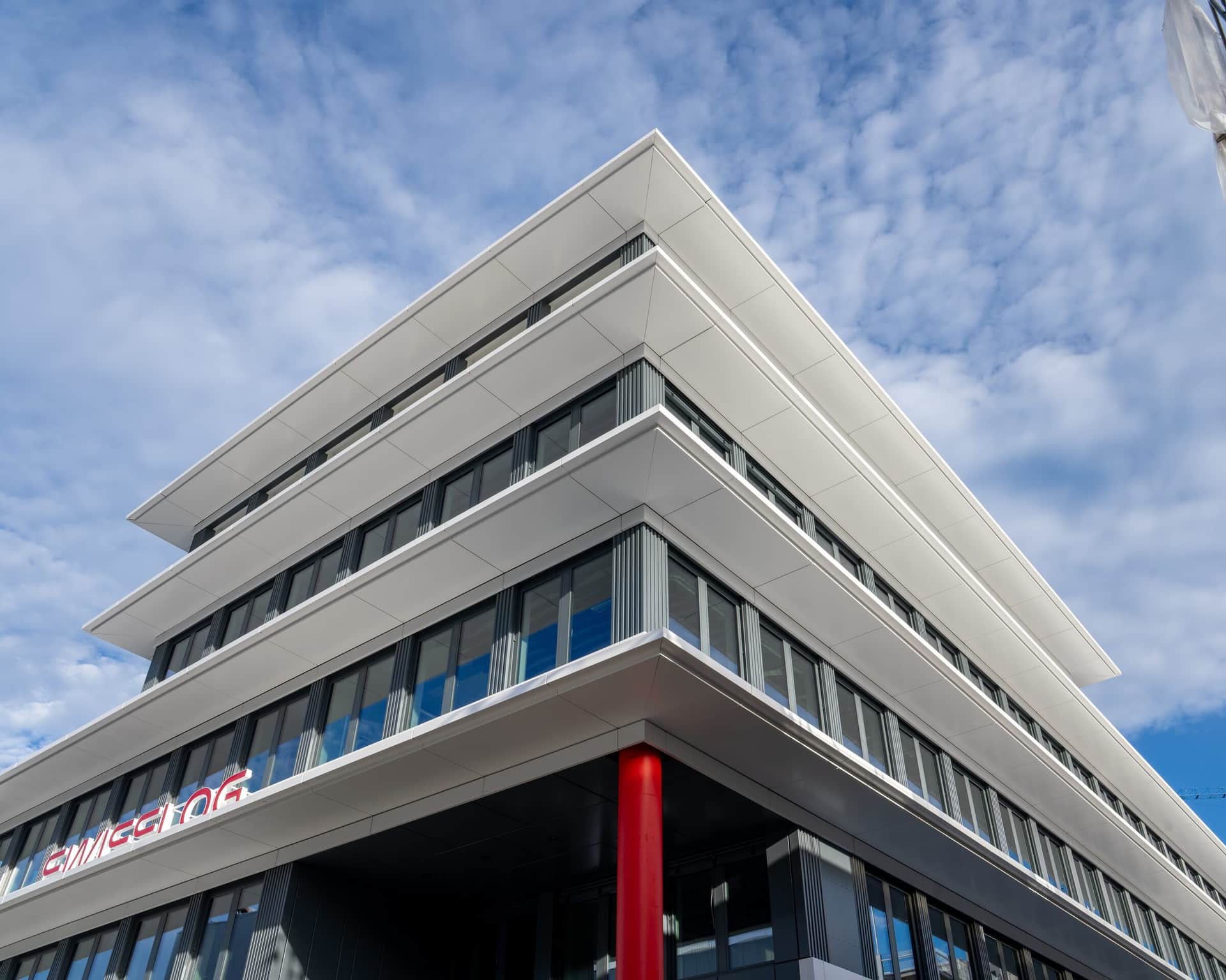 Gebäudeecke einer Metallfassade mit gestaffelten weissen Bändern von unten