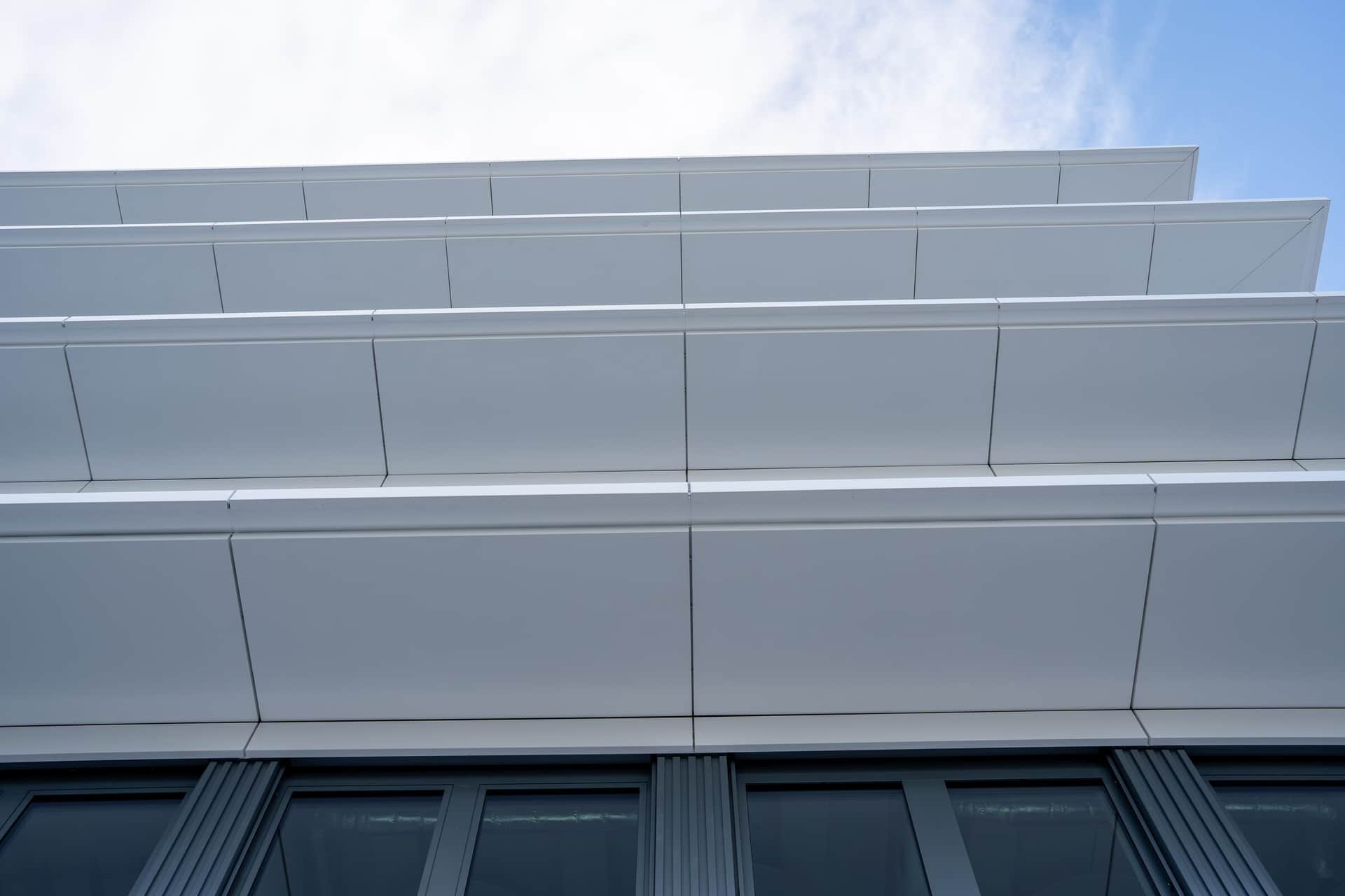 Gestaffelte weisse Bänder einer Metallfassade, frontale Ansicht