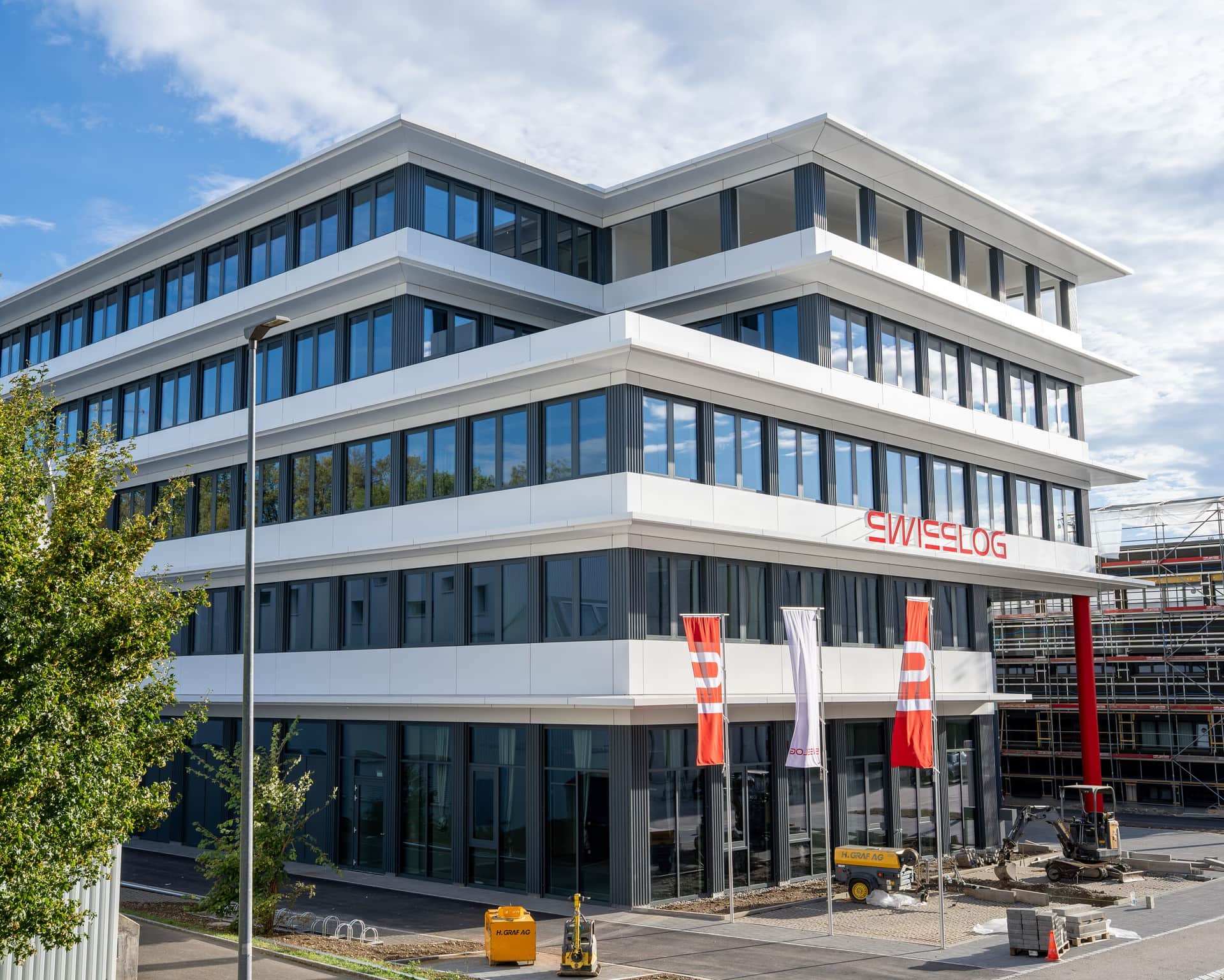 Metallfassade mit Fensterbändern und weissen Brüstungsverkleidungen am Gewerbebau