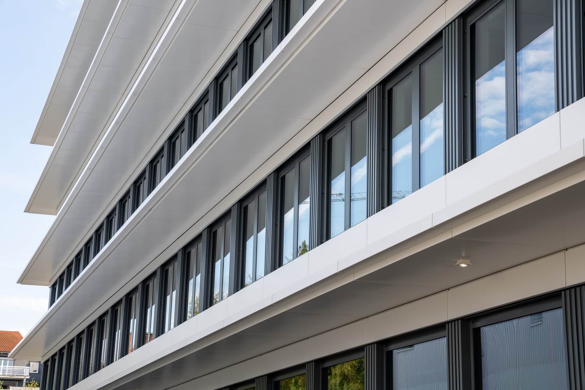 Seitenansicht einer Metallfassade mit Fensterbändern und weissen Brüstungen