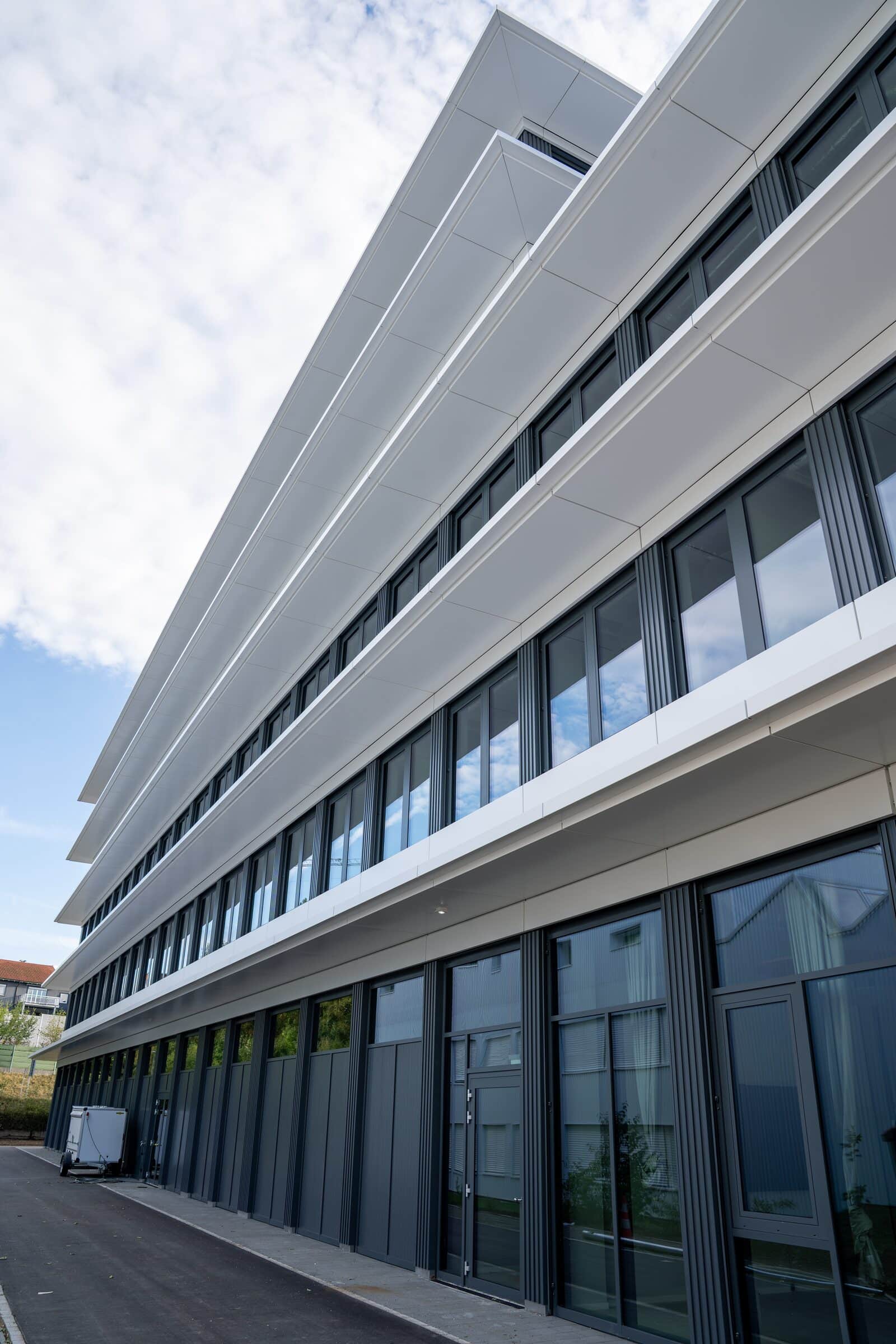 Seitenansicht einer Metallfassade mit weissen Bändern im Hochformat