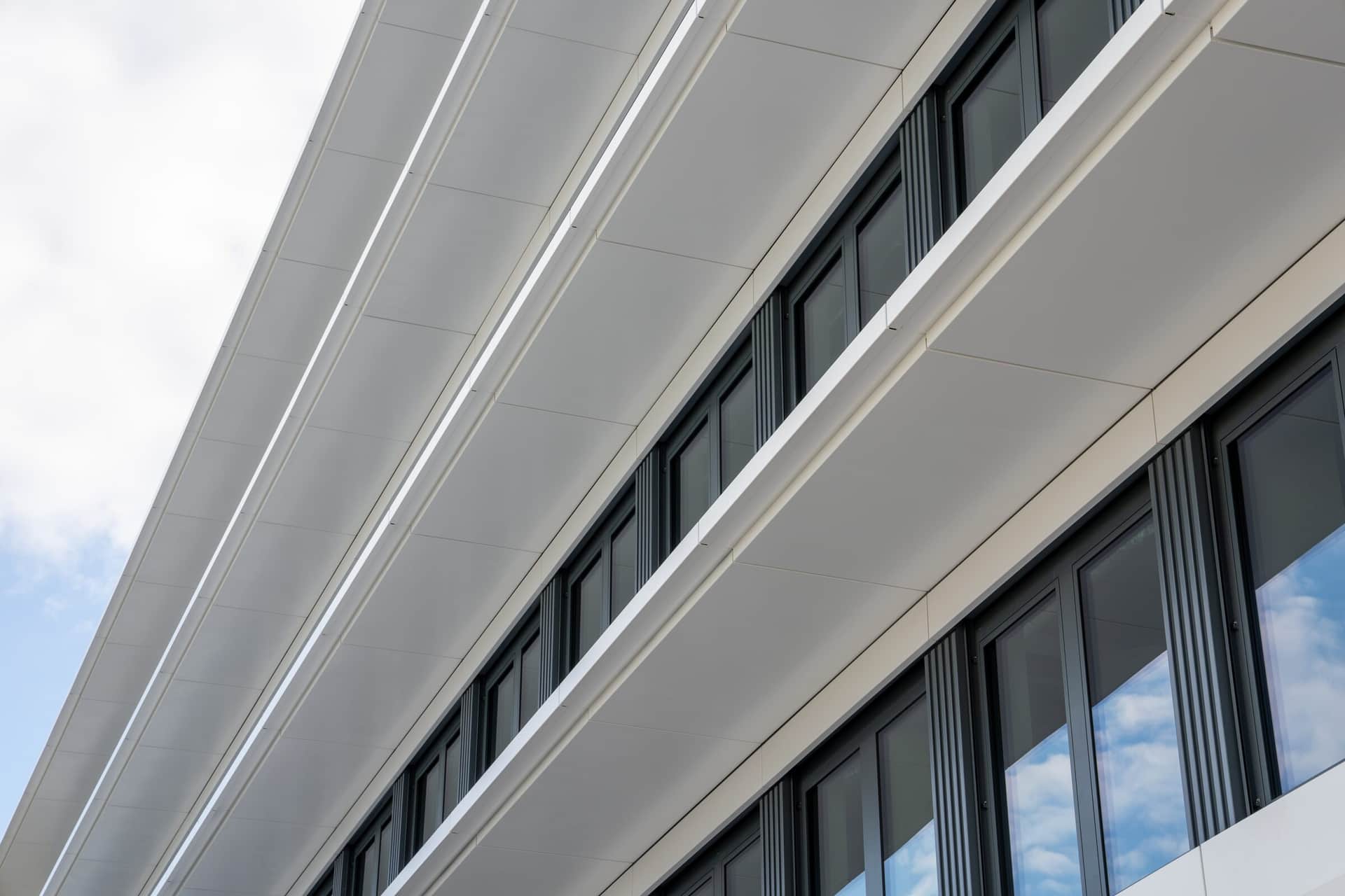 Nahaufnahme weisser Brüstungsbänder einer Metallfassade